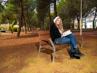Young woman with cheerful fitness sitting on a bench reading a book
