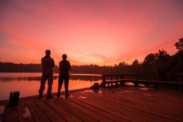 LAKE YEAK LAOM, BAN LUNG DISTRICT, RATANAKIRI, CAMBODIA - 08 December 2009: Couple watch beautiful sunset over volcanic crater lake.