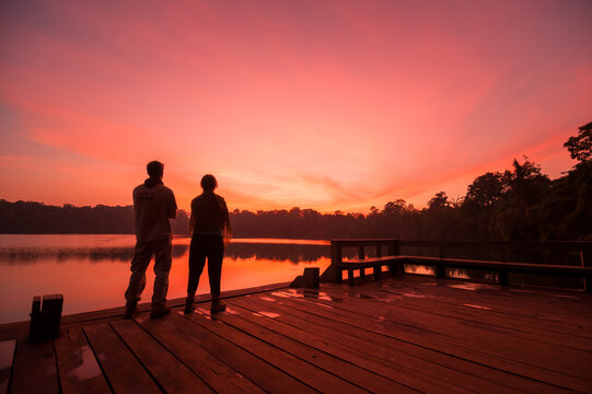LAKE YEAK LAOM, BAN LUNG DISTRICT, RATANAKIRI, CAMBODIA - 08 December 2009: Couple watch beautiful sunset over volcanic crater lake.