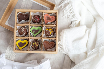 A box of chocolate mix of chocolates stands on the table in the morning light. Beautiful sweet gift for the wedding, for the birthday, for the holiday