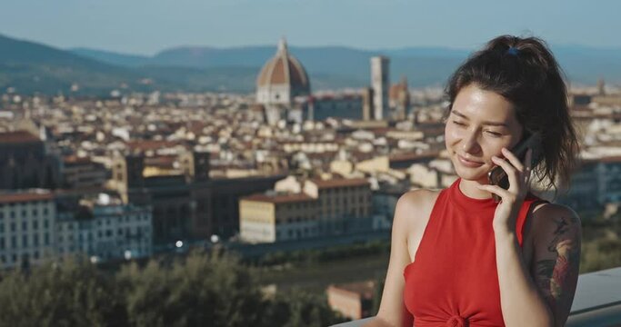 Concept of technology and social media connection. Portrait of smiling asian woman talking on phone or smartphone on background of fantastic Italian view. Pretty girl calling and looking to camera.