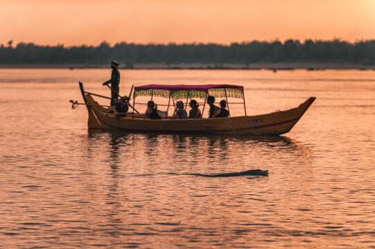 DOLPHIN WATCHING, MEKONG RIVER, KRATIE PROVINCE, CAMBODIA - 31 January 2012: Tourist on boat at sunset miss seeing the elusive irrawaddy dolphin.