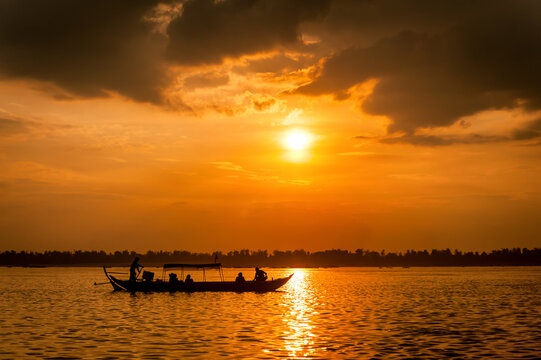 DOLPHIN WATCHING, MEKONG RIVER, KRATIE PROVINCE, CAMBODIA - 31 January 2012: Tourist on boat at sunset looking for the elusive irrawaddy dolphin.