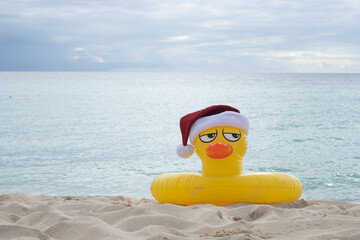 
YELLOW INFLATABLE LIFEGUARD DUCK WITH SANTA CLAUS HAT ON THE SHORES OF A CARIBBEAN BEACH ON A SUNNY DAY