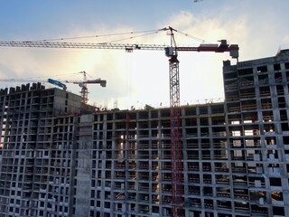 Aerial view construction of a modern office building. The work of building tower cranes against the background of the cityscape