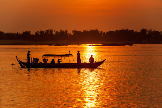 DOLPHIN WATCHING, MEKONG RIVER, KRATIE PROVINCE, CAMBODIA - 31 January 2012: Tourist on boat at sunset looking for the elusive irrawaddy dolphin.