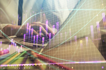 Double exposure of woman hands typing on computer and financial graph hologram drawing. Stock...