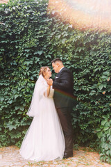 Wedding couple hugs, elegant groom and tender bride with luxurious bouquet of roses