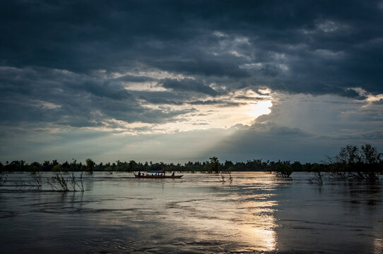 MEKONG RIVER, KRATIE PROVINCE, CAMBODIA - 21 August 2012: Small fishing boat with tourists looking rare fresh water Irrawaddy dolphins in flood plains.