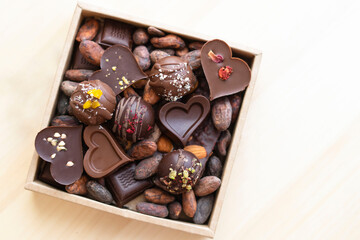 handmade chocolates in a square box with cocoa beans, grains, top view