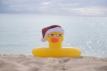 
YELLOW INFLATABLE LIFEGUARD DUCK WITH SANTA CLAUS HAT ON THE SHORES OF A CARIBBEAN BEACH ON A SUNNY DAY