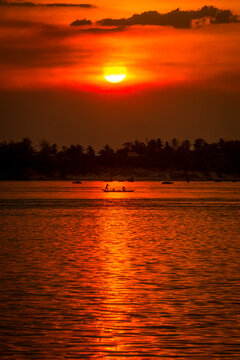 DOLPHIN WATCHING, MEKONG RIVER, KRATIE PROVINCE, CAMBODIA - 26 February 2013: Cambodian fishing boat passes a beautiful mekong river sunset.