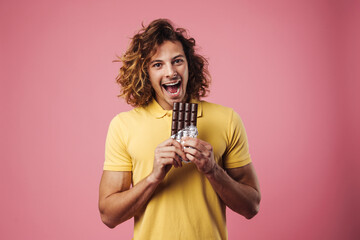 Cheerful handsome guy smiling while eating chocolate