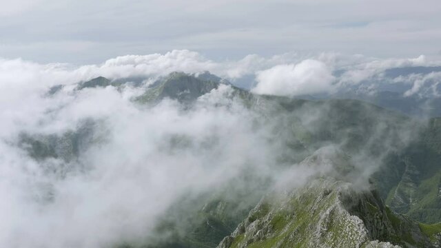 Mist and clouds moving over peaks and ridges of Alpi Apuane mountains in Italy