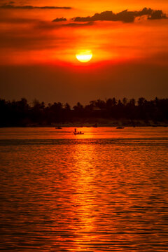DOLPHIN WATCHING, MEKONG RIVER, KRATIE PROVINCE, CAMBODIA - 26 February 2013: Cambodian fishing boat passes a beautiful mekong river sunset.
