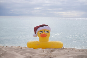 
YELLOW INFLATABLE LIFEGUARD DUCK WITH SANTA CLAUS HAT ON THE SHORES OF A CARIBBEAN BEACH ON A SUNNY DAY