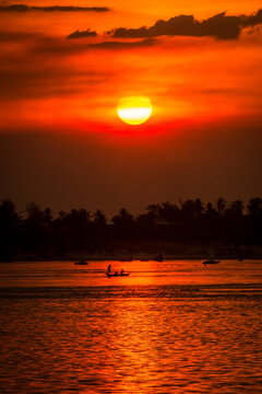 DOLPHIN WATCHING, MEKONG RIVER, KRATIE PROVINCE, CAMBODIA - 26 February 2013: Cambodian fishing boat passes a beautiful mekong river sunset.