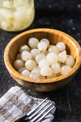 Pickled mini baby onions in wooden bowl.