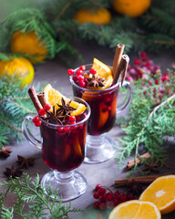 Christmas hot mulled wine with cinnamon, orange slices, anise and red berries on wooden background. Selective focus