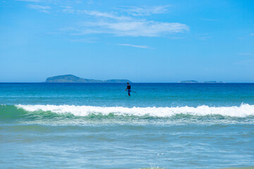 Stand up paddle boarding (SUP) in south atlantic coast. Isolated man doing aquatic sports in a Sunny day of summer. Geriba beach, Buzios, Rio de Janeiro, Brazil.