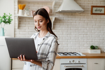 Beautiful pleased woman working with laptop while standing