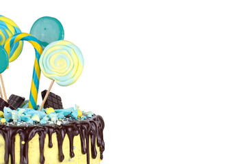 Birthday cake with yellow and blue decor and chocolate icing on a white isolated background. Cake decorated with lollipops copy space.