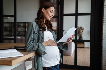 Happy pregnant woman smiling while working with papers