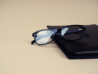 glasses on a black Notepad, stylish background. Copy space for your text.