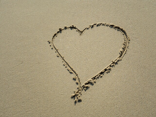 Heart-shaped lines drawn on the sand on the sandy beach background.