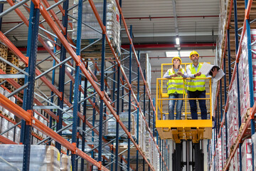 Warehouse workers on lift work platform checking inventory