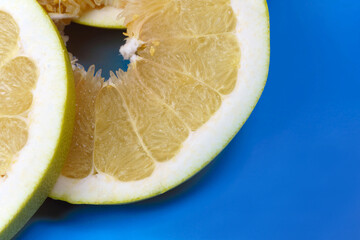 Round pomelo slices on a light blue background. Citrus yellow fruit.