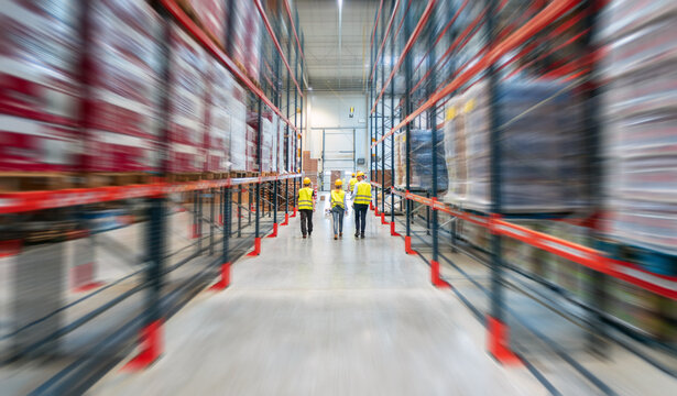 Warehouse workers walking between tall shelves full of packages