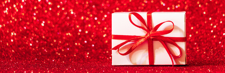 Gift boxes on red glittering background. Christmas concept, banner format.