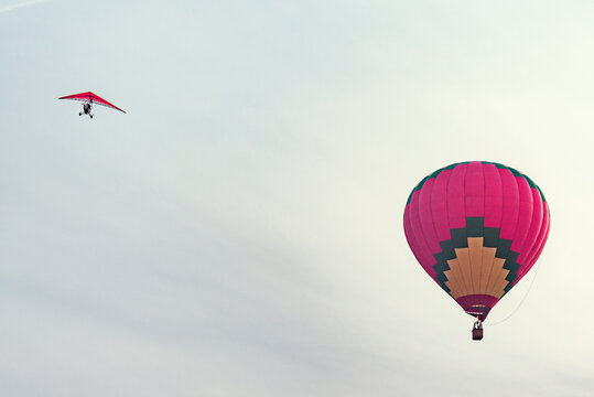 Morning flight of the hot air balloon and deltaplane in the sunset sky.