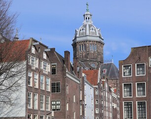 Fototapeta premium Old Canal Houses with Church Tower in Amsterdam's Red Light District