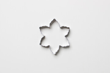 cookie cutter in form of snowflakwe on white colored paper background. isolated. close up. mock up