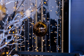 A Merry Christmas ornaments hanging in front of a bokeh background of fairy lights.shiny Christmas balls on threads in dark interior.Holiday concept.Alternative ,creative decoration for new year.