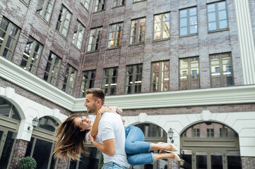 Fashion outdoor romantic portrait of beautiful young couple in love and hugs on the street.