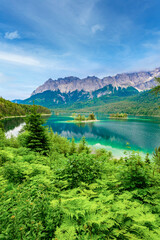 Obraz na płótnie Canvas Small islands with pine-trees in the middle of Eibsee lake with Zugspitze mountain. Beautiful landscape scenery with paradise beach and clear blue water in German Alps, Bavaria, Germany, Europe.