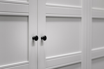Minimal white closet or wardrobe with black door's handle. Interior  object photo, Close-up and selective focus at the knob handle.