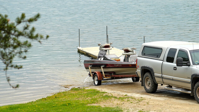 CLEARWATER CO, MN - 23 MAY 2020: Pickup truck pulling fishing boat and trailer out of the water at the shore of a Minnesota lake.
