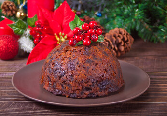 Fototapeta na wymiar Traditional Christmas pudding with holly on top on the wooden background