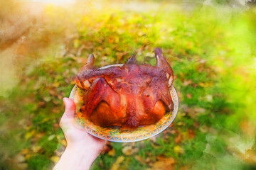 Man holding a dish of fried chicken. Grilled whole chicken on background of the garden, close-up. Vector watercolor illustration.
