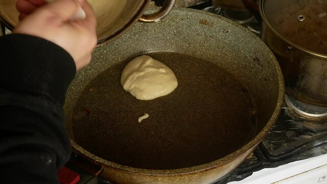 Fries pancakes in a skillet.Pours batter with a ladle.Flour sweet dessert.