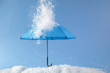 Blue umbrella on blue background with snow. Blue monday concept.