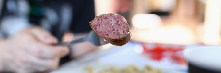 On fork is piece of fried sausage. How to fry a sausage correctly concept