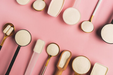 Collagen powder and pills spoons on pink background. Extra protein intake. Natural beauty and health supplement for skin, bones, joints and gut. Plant or fish based. Flatlay, top view. Copy space.