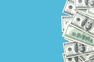 American 100 dollar bills on a light blue colored background. Cash, currency. Copy space, top view, banner. Business, finance concept. Savings