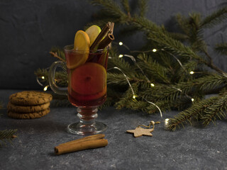 A glass of hot mulled wine, spices, cinnamon, and christmas tree on a black background