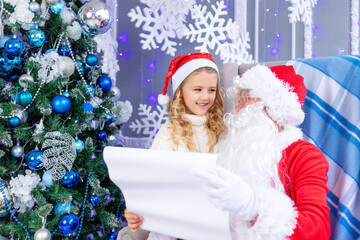 Fototapeta na wymiar Santa Claus reads a letter from a child at the Christmas tree, new year and Christmas concept